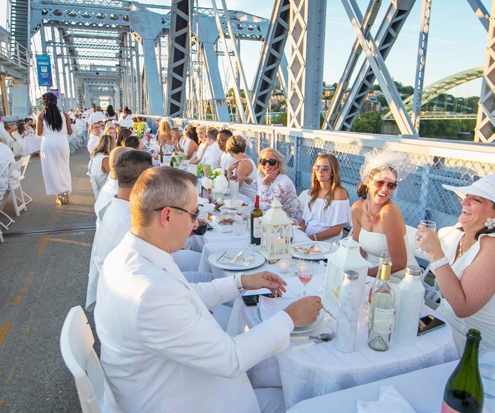 Dinner en Blanc on the Purple People Bridge with everyone wearing white and dining at long tables that span the bridge
